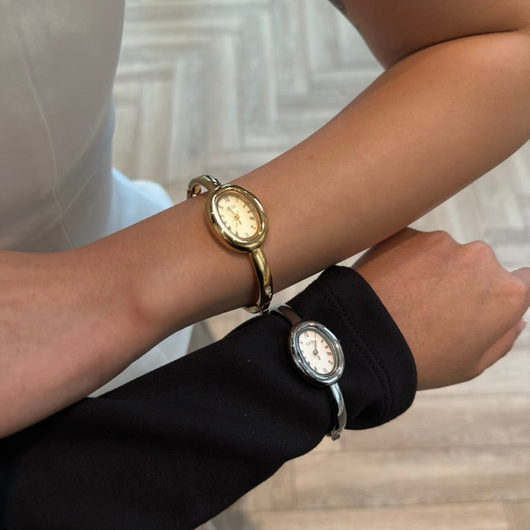 Two gold wristwatches on a person's wrist with a blurred background