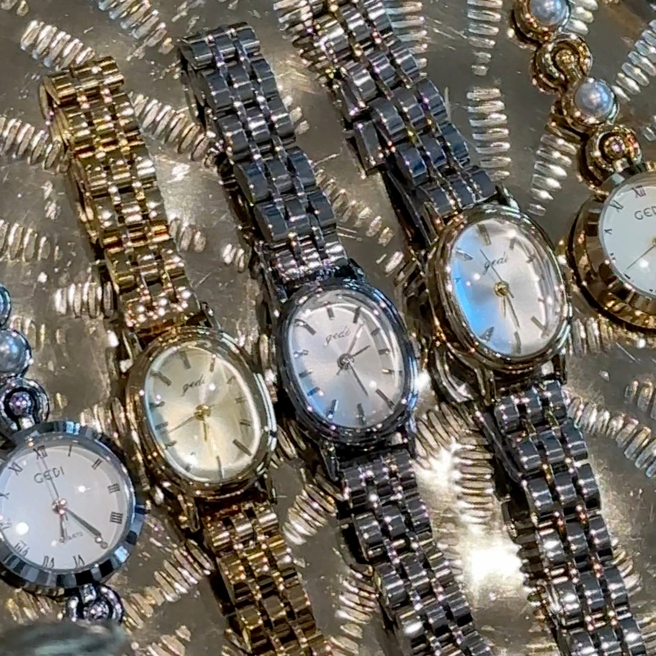 Collection of watches with decorative straps on a textured surface