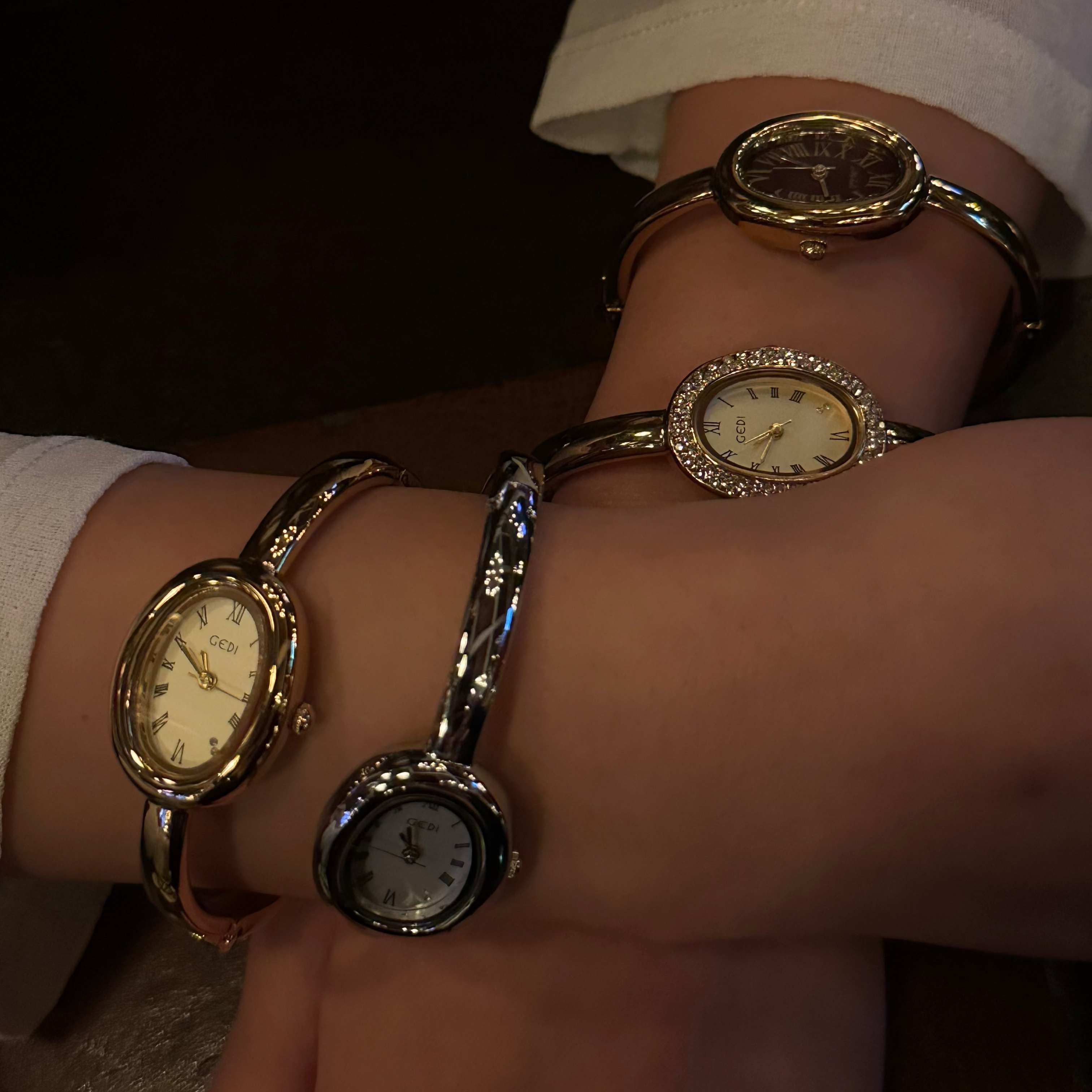 Close-up of a wrist wearing multiple gold watches with a dark background