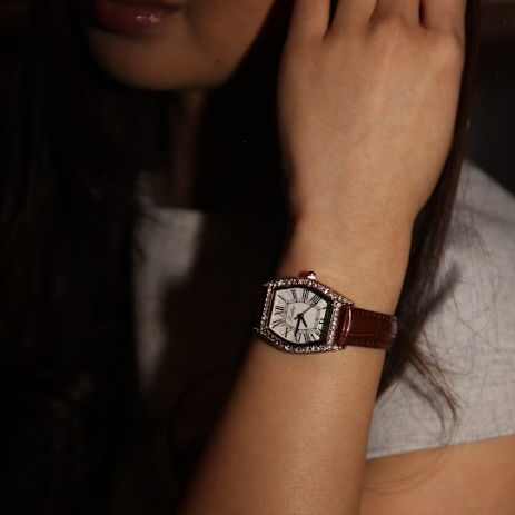 Close-up of a person wearing a watch with a brown leather strap.