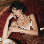 Woman in a brown dress sitting at a table with a glass of red wine in an elegant setting.