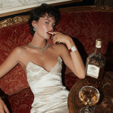 Woman in a white dress sitting on a red couch with a bottle of Johnnie Walker and a glass.